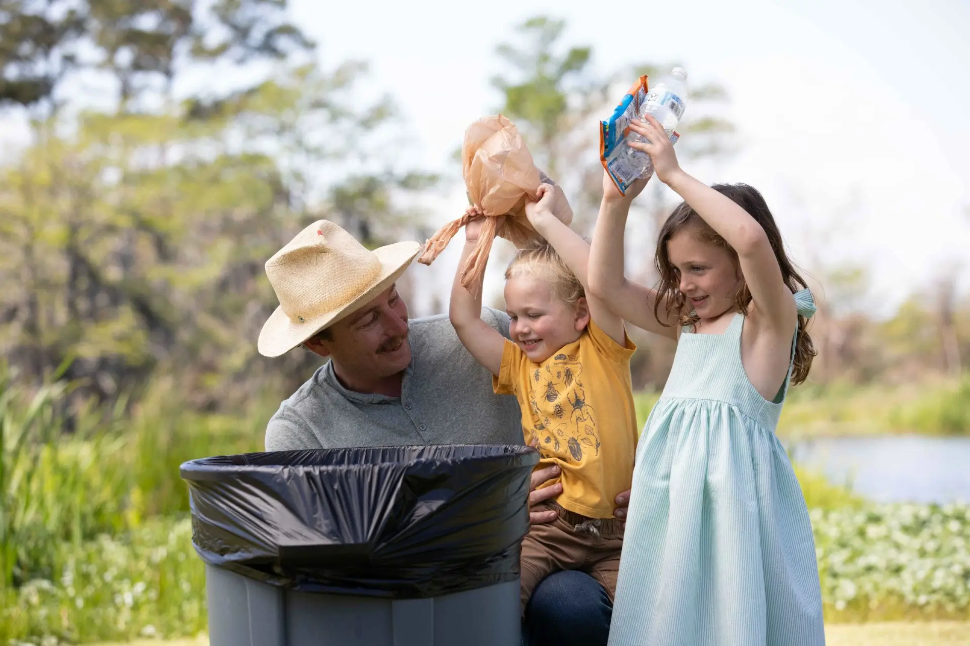 Kids cleaning up park by throwing away trash